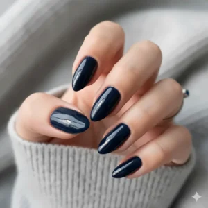 Close-up of glossy, dark navy blue nail polish on almond-shaped nails, perfect for an evening look.