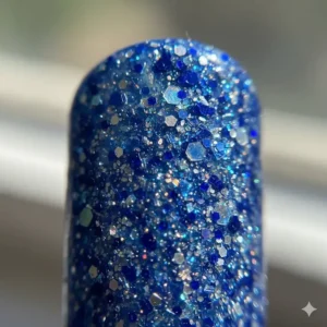 Macro shot highlighting the fine and chunky glitter particles in the blue nail polish.