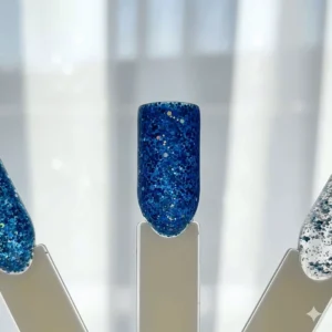 Swatch of shimmering blue glitter nail polish applied to a testing wheel.