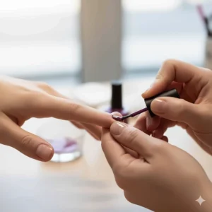 A nail artist carefully applying plum nail polish to a fingernail with a precision brush.