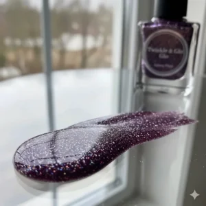 Swatch showing a shimmering dark purple nail polish with fine glitter accents.