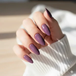 Elegant application of a glossy light grape polish on long, almond-shaped fingernails.