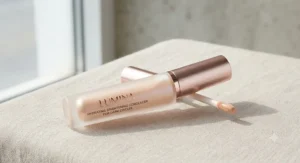 A sleek tube of hydrating brightening concealer for dark circles resting on a neutral background.