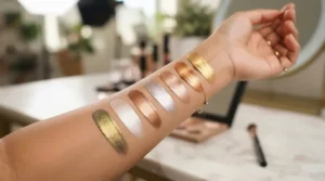 Swatches from a highlighter palette for deep skin tones showcasing intense metallic payoff on rich skin.